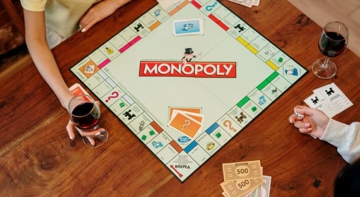 Two people playing monopoly on a wooden table