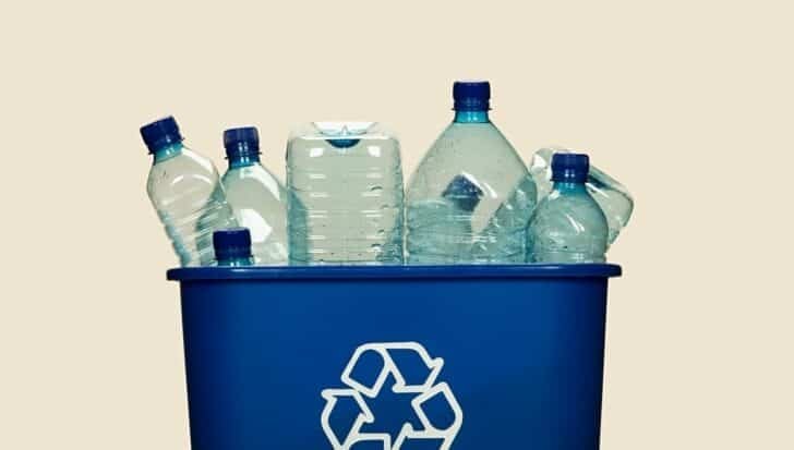 Plastic bottles in a blue recycling bin with a recycling symbol