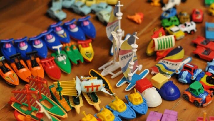 Collection of small colorful children's toy vehicles and boats on a wooden surface