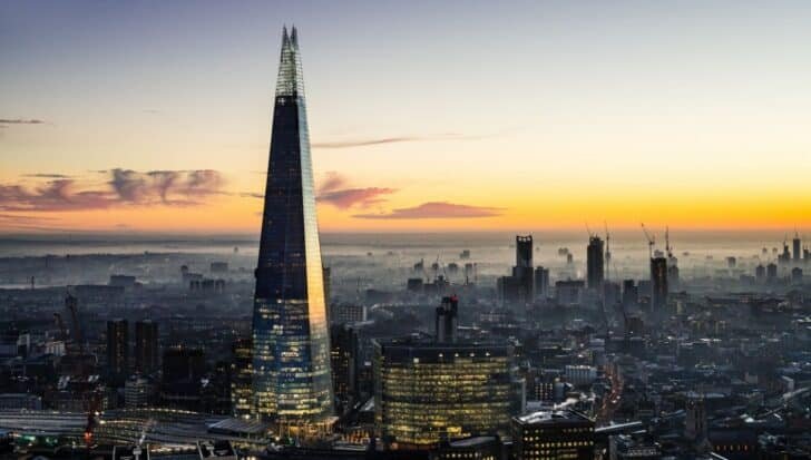 The Shard towering over the London skyline at dusk with a vibrant sunset in the background, highlighting its modern architecture and reflecting light with the cityscape below