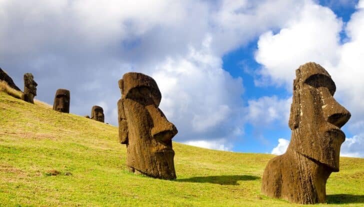 Several moai statues standing on a grassy hillside under a partly cloudy sky on Easter Island