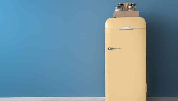 Yellow refrigerator against a blue wall, with jars and utensils on top, related to the synthesis of chlorofluorocarbons