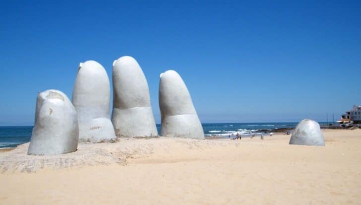 Large concrete sculpture resembling fingers emerging from the sand on a beach in Punta del Este, Uruguay, known simply as The Hand