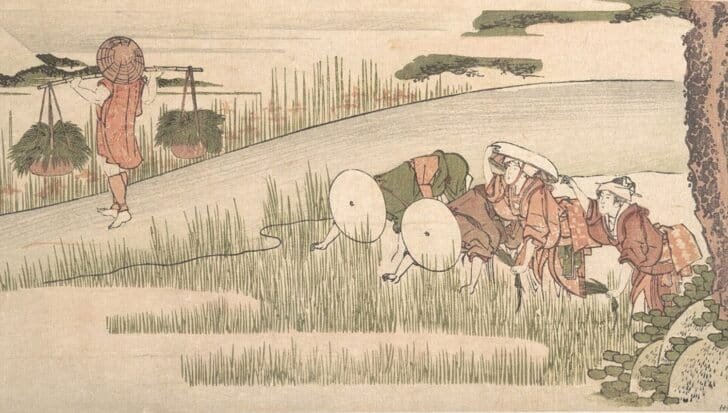 Traditional Japanese farmers working in rice fields, with one carrying baskets of rice on a pole
