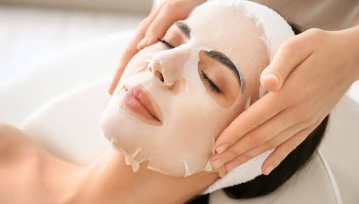 Person with a sheet mask applied to their face during a skincare treatment