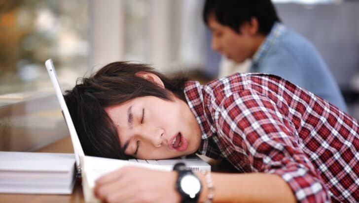 Student sleeping on a laptop in a classroom
