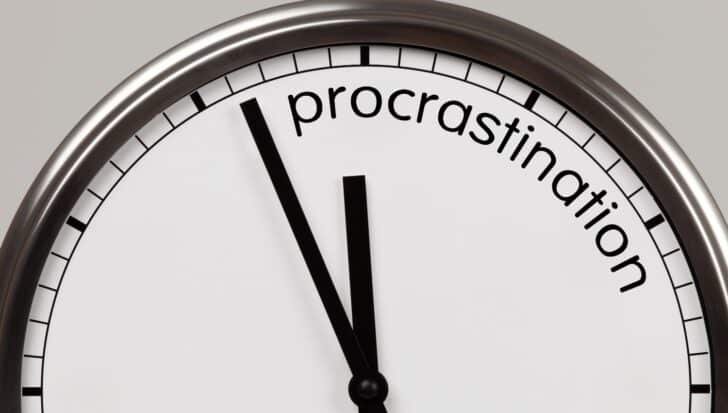 Close-up of a clock with the word 'procrastination' replacing numbers
