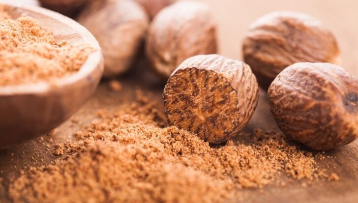 Whole and ground nutmeg on a wooden surface