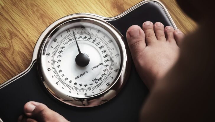A person standing on a scale indicating weight gain related to stress