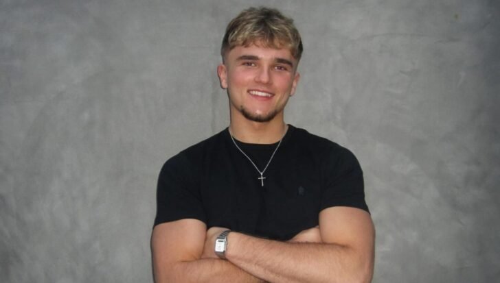 Hendrik Christoffersen smiling with arms crossed in front of a gray background