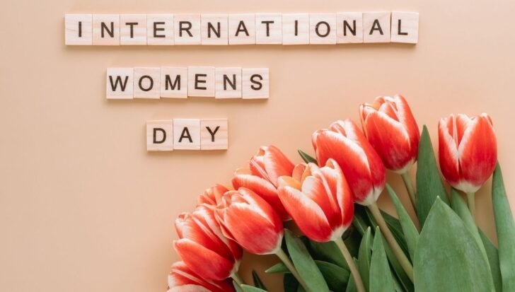 Wooden tiles spelling 'International Women's Day' with red and white tulips